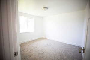 Unfurnished room featuring light colored carpet and baseboards