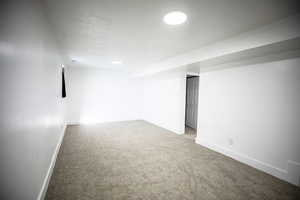 Finished below grade area featuring light carpet and baseboards