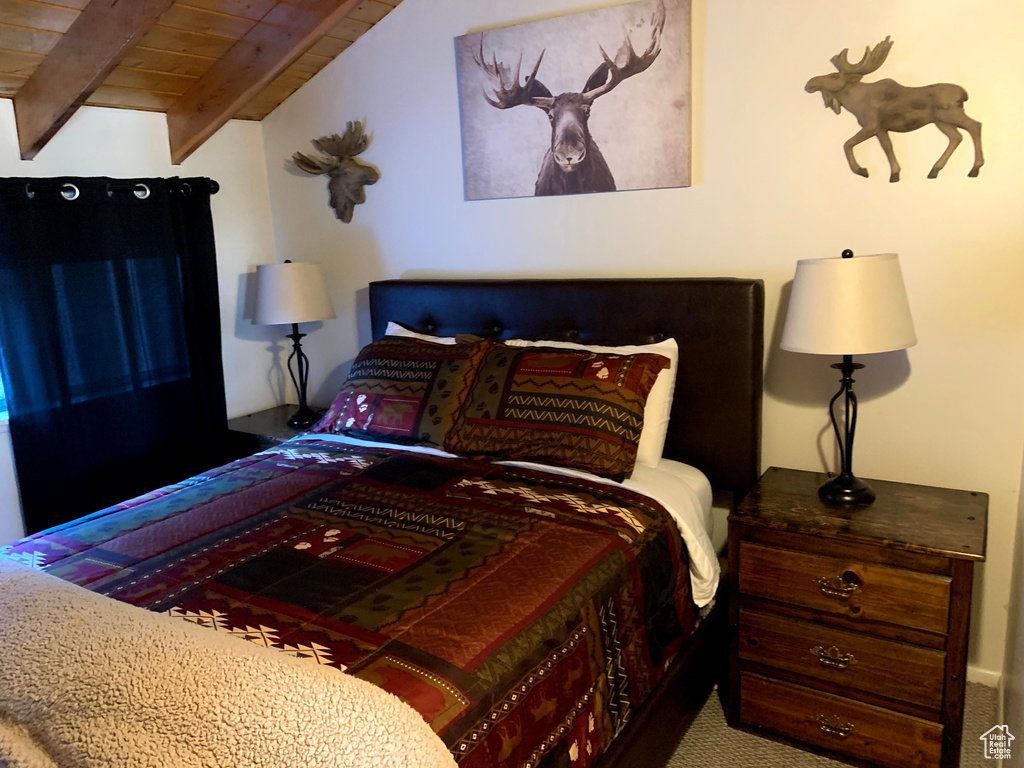 Bedroom with a wood ceiling with exposed beams and carpet flooring