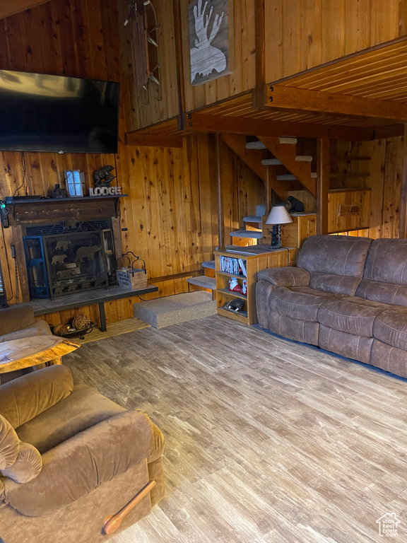 Living room with stairway, wood finished floors, and wood walls