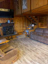 Living room with stairway, wood finished floors, and wood walls