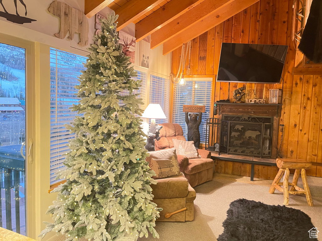 Carpeted living room featuring wooden walls and a fireplace with raised hearth