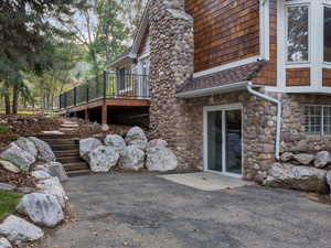View of side of home with stone siding and a wooden deck