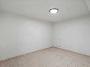 Carpeted empty room featuring baseboards.