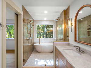 Primary bathroom with a wet-room, freestanding tub, vanity, and a tile shower