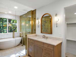 Primary bathroom with a wet-room, freestanding tub, vanity, and a tile shower