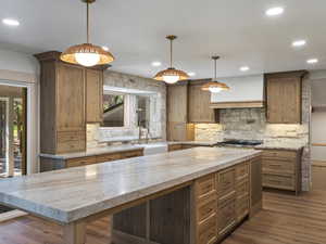 Kitchen featuring abundant stone, quartzite counters, handmade cabinets, and pendant lighting.