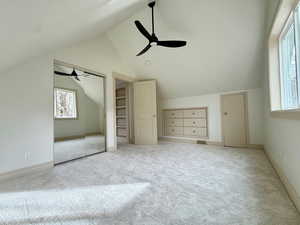 Upstairs bedroom with lofted ceiling, light colored carpet, a textured ceiling, and a ceiling fan