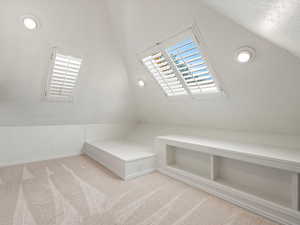 Additional living space or bedroom featuring lofted ceiling and light carpet.