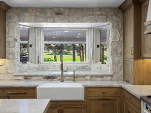 Kitchen featuring abundant stone, quartzite counters, handmade cabinets, and pendant lighting.