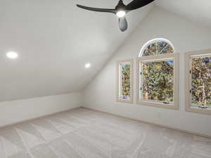 Upstairs bedroom with vaulted ceiling, light colored carpet, and ceiling fan