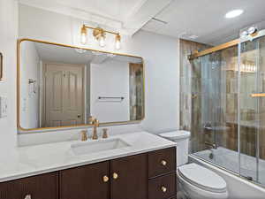 Basement bathroom with a textured ceiling, bath / shower combo with glass door, and vanity.