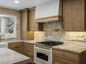Kitchen featuring abundant stone, quartzite counters, handmade cabinets, and pendant lighting.