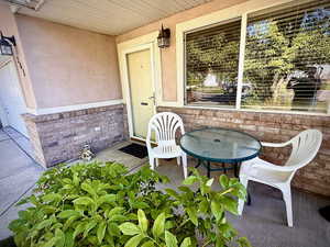 View of exterior entry with covered porch, stucco siding, and brick siding