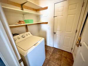 Washroom with washer / clothes dryer and dark tile patterned floors