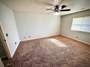 Carpeted spare room featuring a textured ceiling and ceiling fan