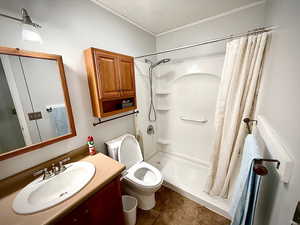 Bathroom with vanity, a shower stall, dark tile patterned floors, a textured ceiling, and ornamental molding