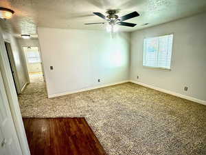 Spare room with a textured ceiling, wood finished floors, and ceiling fan