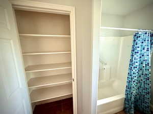 Full bathroom featuring dark tile patterned flooring and shower / bath combo with shower curtain