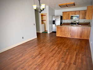 Kitchen featuring a peninsula, open floor plan, a chandelier, stainless steel appliances, and tasteful backsplash