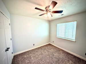 Unfurnished bedroom with a textured ceiling, a closet, a ceiling fan, and carpet