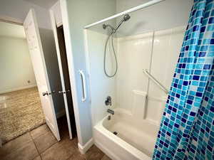 Bathroom featuring shower / bath combo with shower curtain, dark tile patterned flooring, and dark carpet