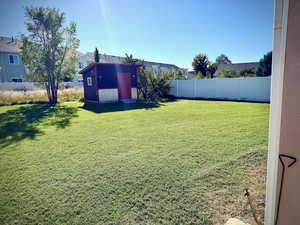 Fenced backyard featuring a storage shed and a residential view
