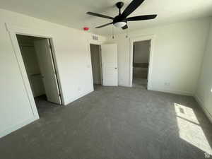 Unfurnished bedroom with a spacious closet, ensuite bath, carpet floors, ceiling fan, and a textured ceiling