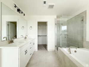 Bathroom featuring a shower stall, a bath, double vanity, light tile patterned floors, and a textured ceiling