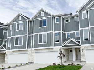 View of front of home featuring stone siding, a garage, concrete driveway, and board and batten siding