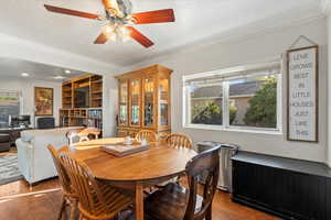 Dining room with crown molding, wood finished floors, a textured ceiling, and a ceiling fan
