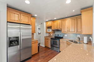 Kitchen featuring stainless steel appliances, light stone countertops, dark wood-style floors, tasteful backsplash, and recessed lighting