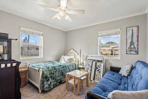 Carpeted bedroom featuring ornamental molding and a ceiling fan
