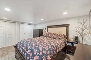 Bedroom with light colored carpet, two closets, and recessed lighting