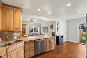 Kitchen featuring light stone countertops, dark wood finished floors, dishwasher, recessed lighting, and a peninsula