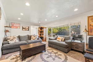 Carpeted living room featuring ornamental molding and recessed lighting