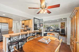 Dining room featuring dark wood finished floors, ornamental molding, ceiling fan, and recessed lighting