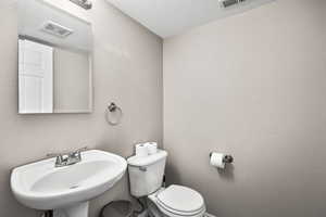Half bath with a textured wall and a textured ceiling