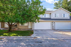 View of front facade with driveway, a shingled roof, and an attached garage
