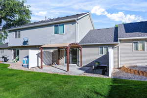 Rear view of house with a patio, roof with shingles, and a lawn