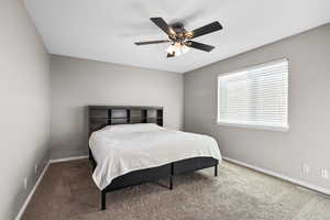 Carpeted bedroom featuring a ceiling fan and baseboards