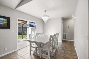 Dining room with a textured wall, a chandelier, a textured ceiling, and tile patterned flooring