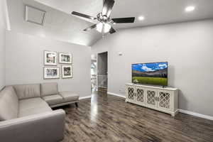 Living area with lofted ceiling, dark wood-type flooring, ceiling fan, and a textured ceiling