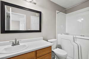 Bathroom with a textured wall, vanity, and shower / bath combination