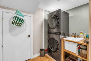 Laundry area featuring light wood-style flooring, stacked washer / dryer, and recessed lighting