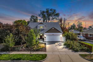 View of front facade featuring concrete driveway, a garage, and roof with shingles