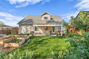 Rear view of house featuring a shingled roof, a fenced backyard, a patio, and a garden