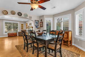 Dining room with arched walkways, light wood finished floors, ceiling fan, and a fireplace