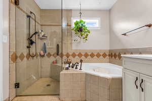 Bathroom featuring a bath, a stall shower, and vanity