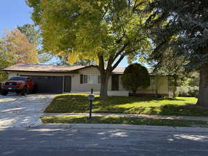 Ranch-style house with concrete driveway, a front lawn, and a garage